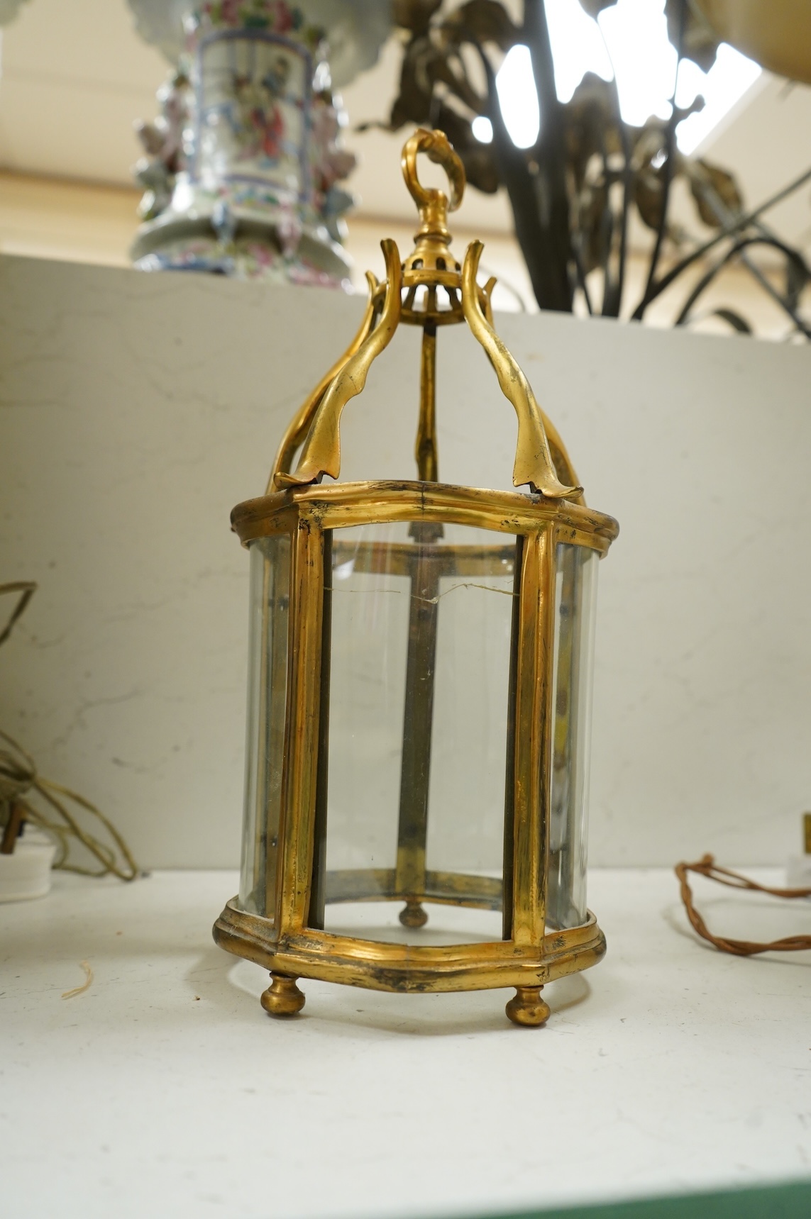 A pair of table lamps and shades, 92cm high, the lamps decorated in gold and green tones painted with birds and flowers, together with a small glass and brass hall lantern (3).